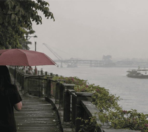 Pedestrian walking along a hazy riverside promenade in Sarawak